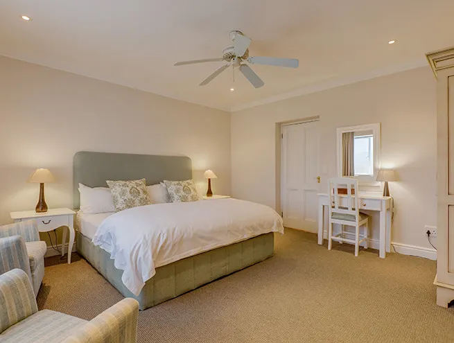 Bedroom with large bed two lamps desk chair and ceiling fan