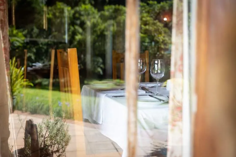 Reflection of a dining table with wine glasses in a garden setting