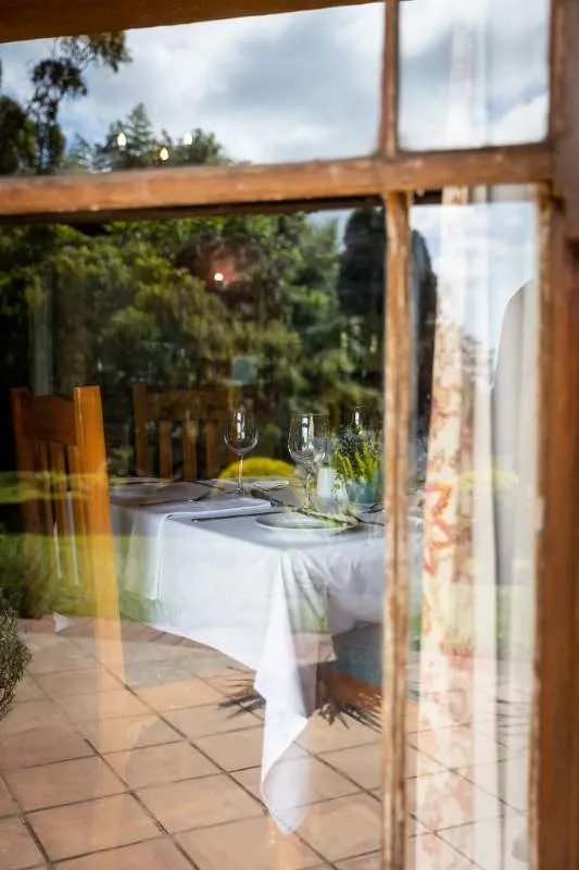Reflection of a set dining table in a window with a garden view