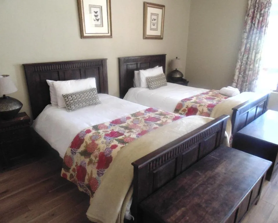 Two twin beds in a bedroom with floral bedding and wooden furniture