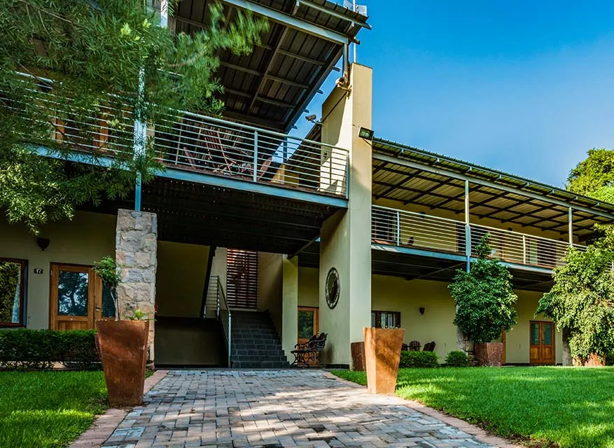 Modern twostory building with balcony stone pillars and wellmaintained garden