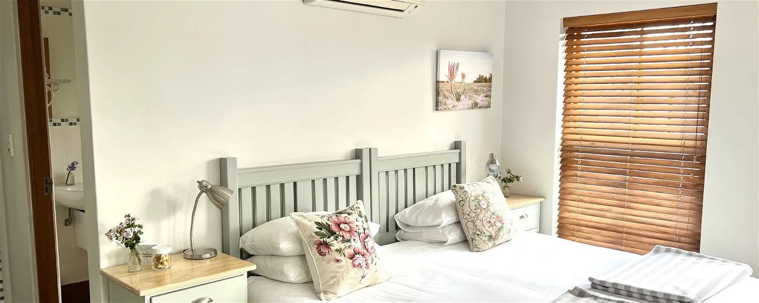 Cozy bedroom with a double bed floral pillows and wooden blinds on window