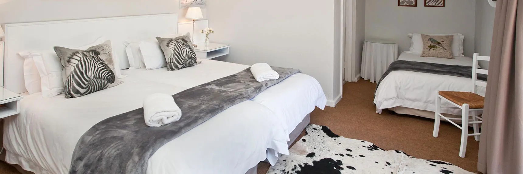 Bedroom with a large bed a single bed and a cowhide rug