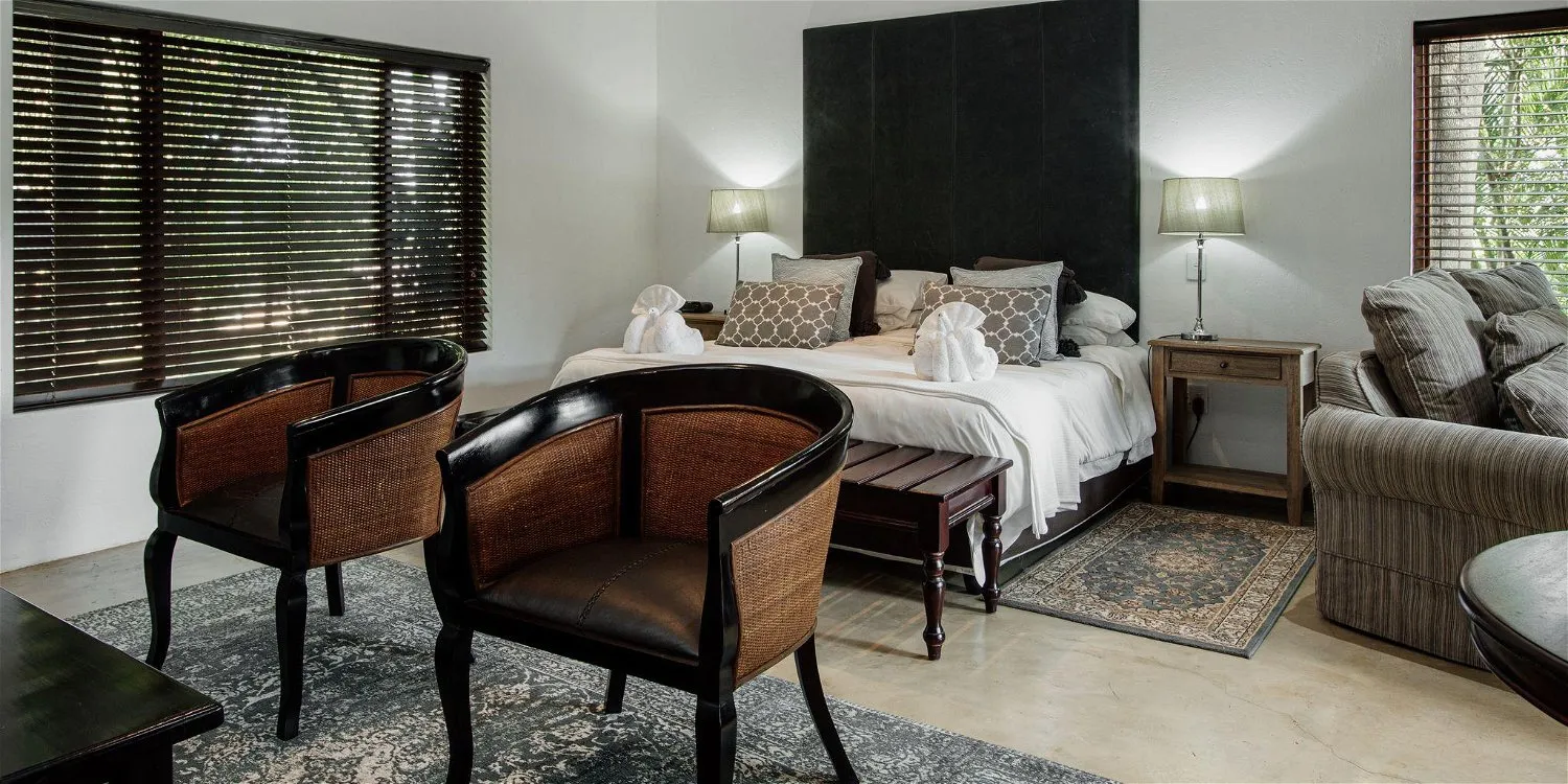 Bedroom with two armchairs bed and sofa natural light from windows