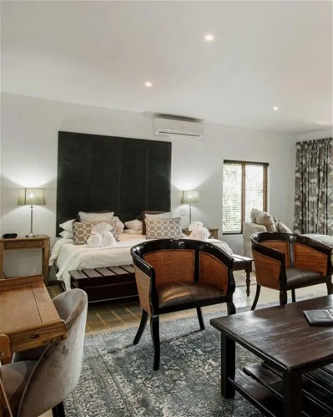 Modern bedroom with large bed chairs and a desk featuring a patterned rug