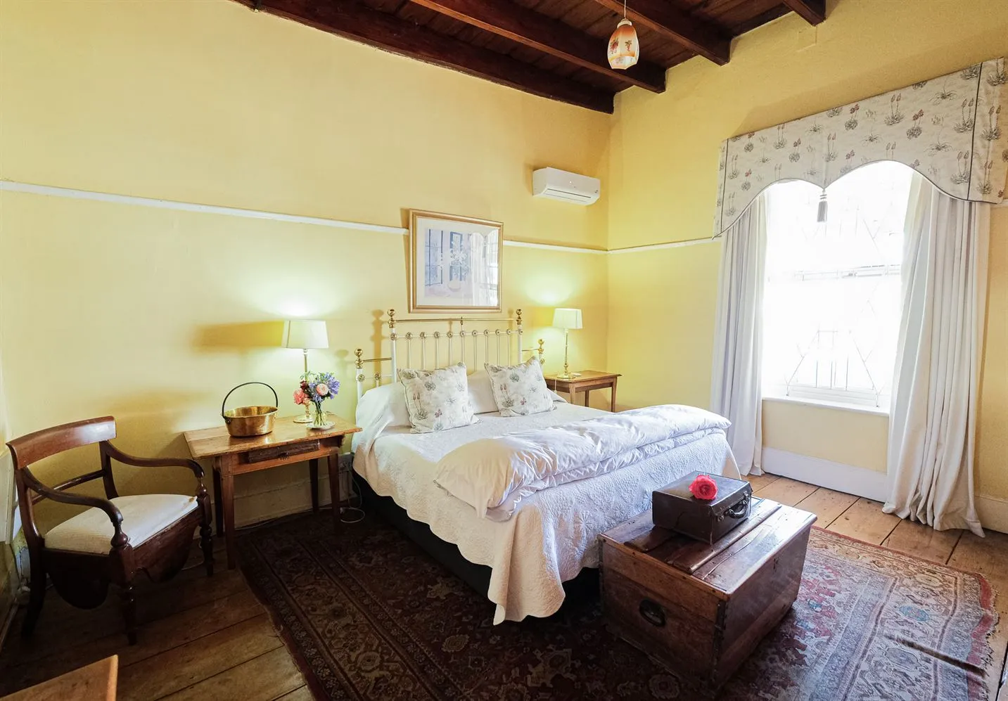 Cozy bedroom with a large bed wooden furniture and a window with curtains