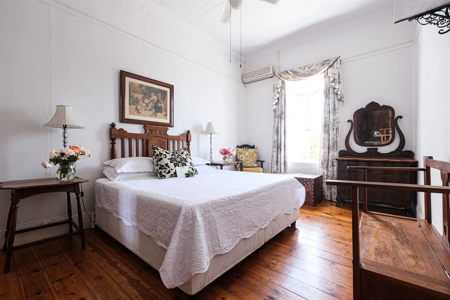 Cozy bedroom with a neatly made bed wooden floor and vintage furniture