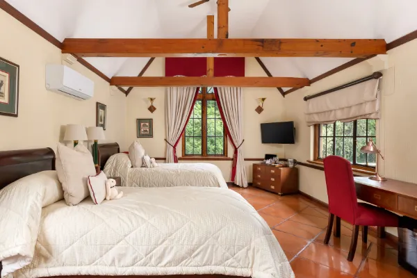 Cozy bedroom with two beds red chair desk and large window