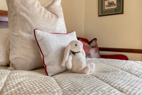 Stuffed bunny on a bed with pillows in a cozy room