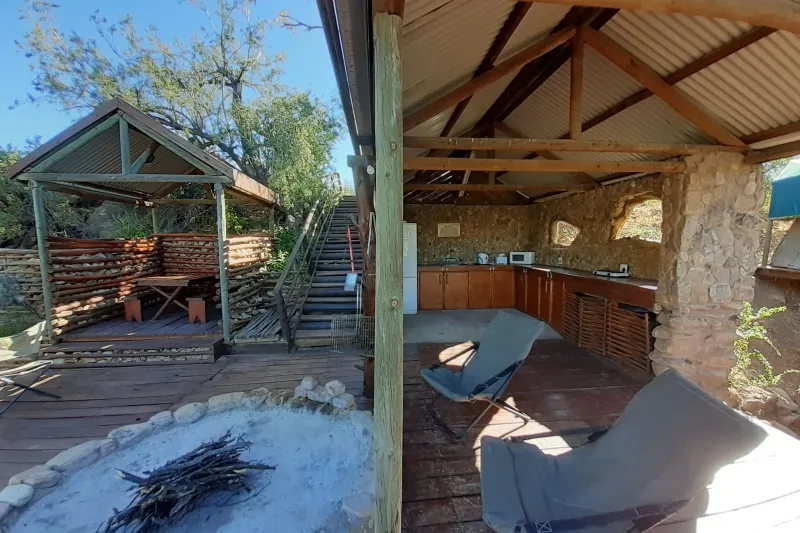 Outdoor kitchen and seating area with rustic wooden structures and stone walls