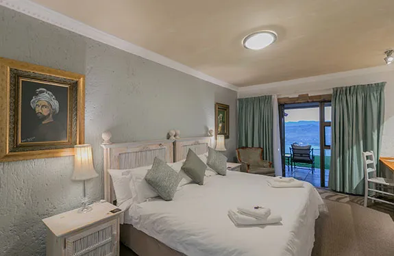 Cozy bedroom with large bed artwork and view of a lake through a window