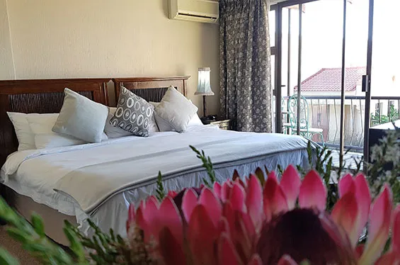 Cozy bedroom with large bed pillows and view of garden through sliding doors