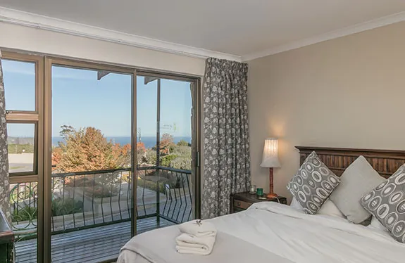 Bedroom with large windows overlooking a scenic view decorated with patterned pillows