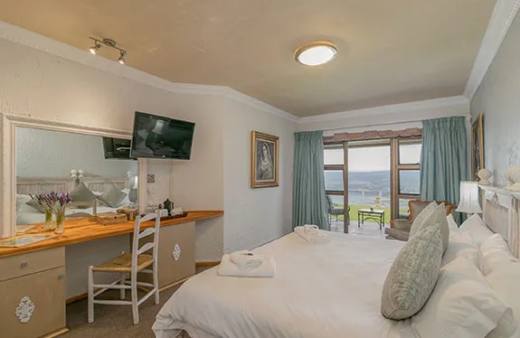 Cozy bedroom with large bed desk TV and scenic view through window