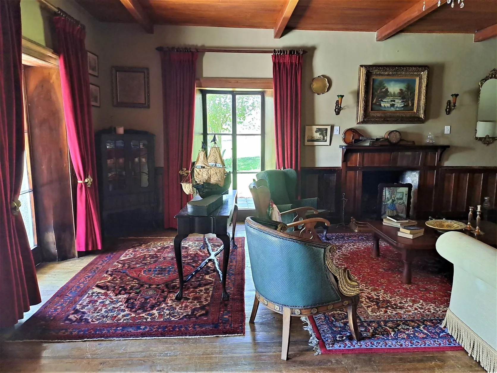 Cozy living room with fireplace armchairs and vibrant rugs featuring wooden ceiling