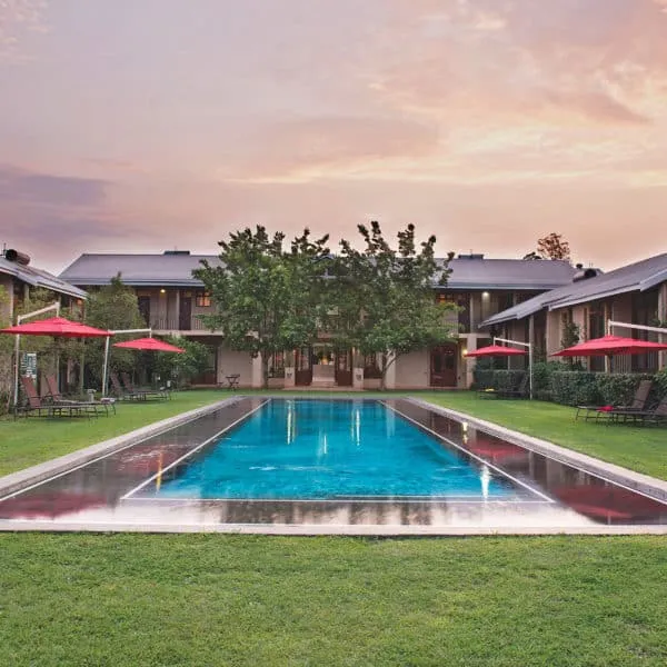 Swimming pool in front of a large building with lounge chairs and umbrellas