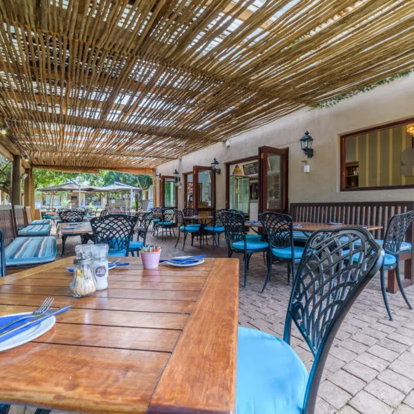 Outdoor restaurant with wooden tables wicker chairs and a thatched roof