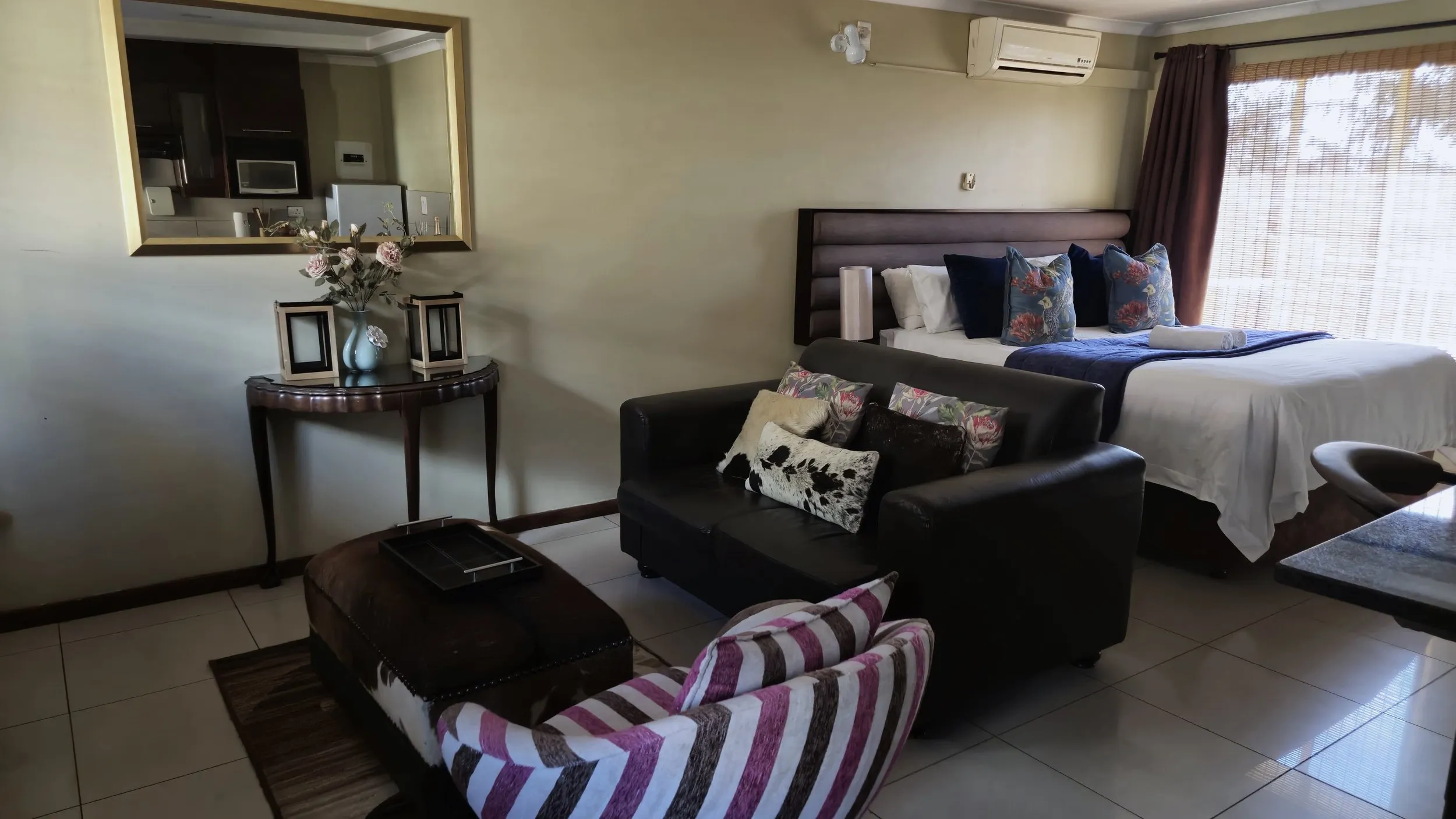 Cozy bedroom with a bed sofa and armchair decorated with pillows and flowers