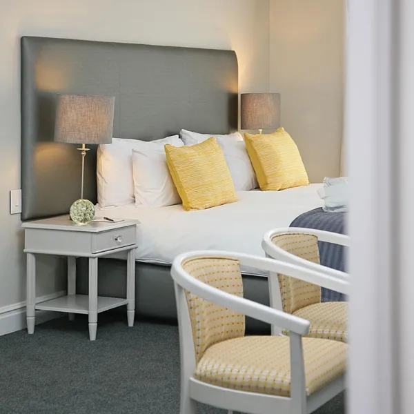 Bedroom with a bed two bedside tables with lamps and two yellow chairs