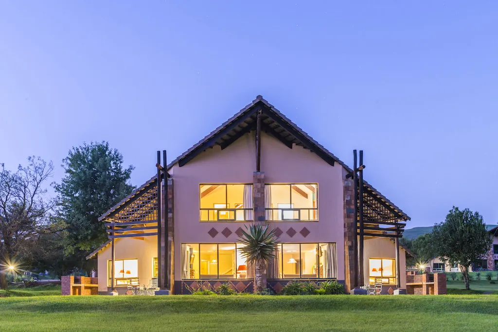 Modern twostory house with large windows and lights on set in a grassy area