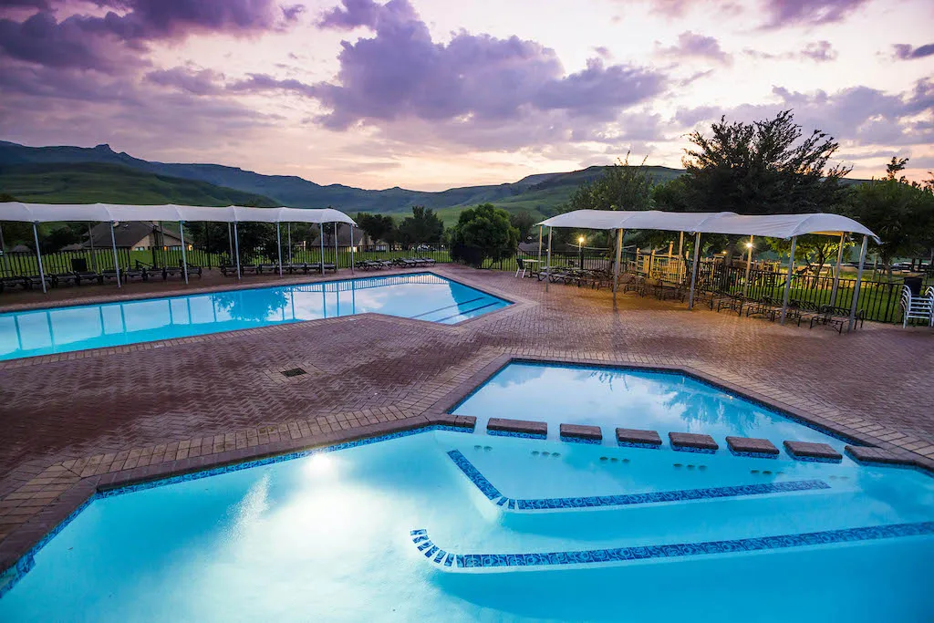 Outdoor swimming pools at sunset with surrounding greenery and seating areas