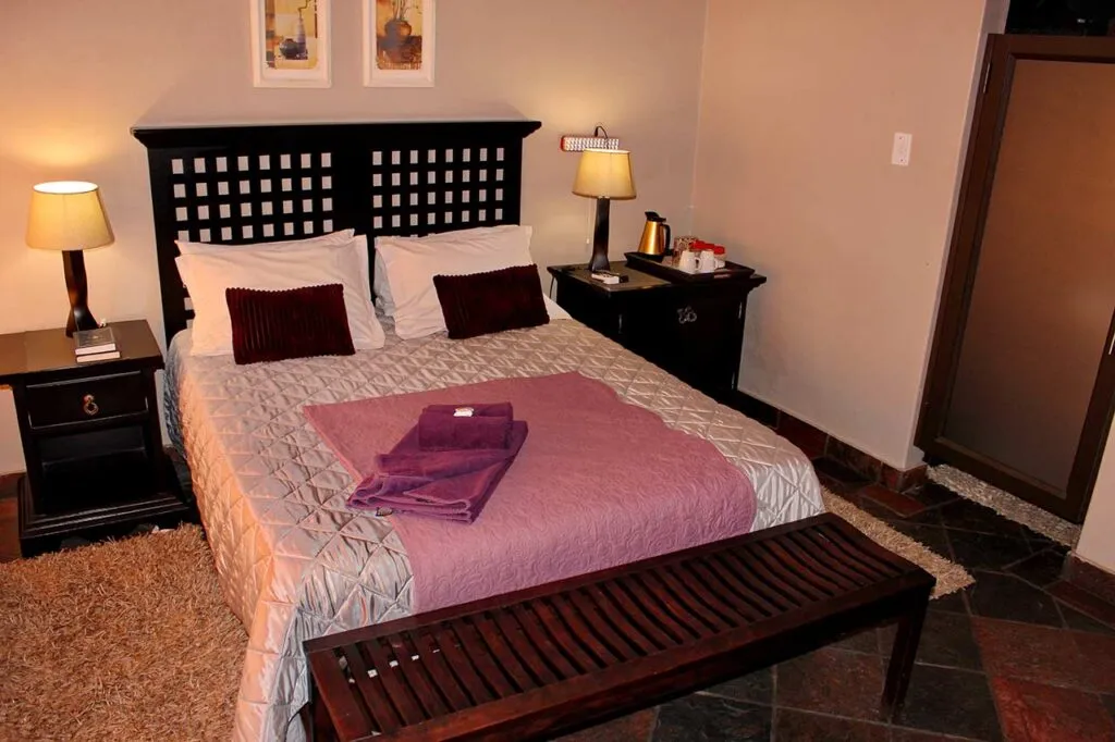 Cozy bedroom with a neatly made bed bedside tables and a wooden bench