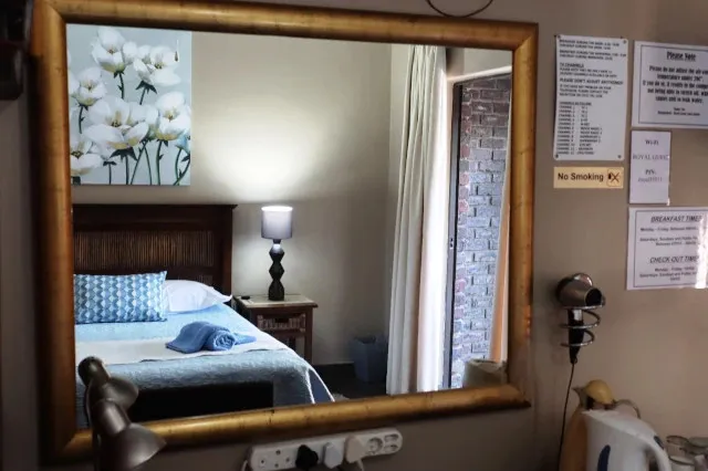 Mirror reflecting a bedroom with a bed lamp and brick wall