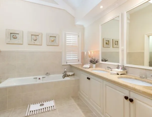 Modern bathroom with double sink large mirror and bathtub with tiled walls