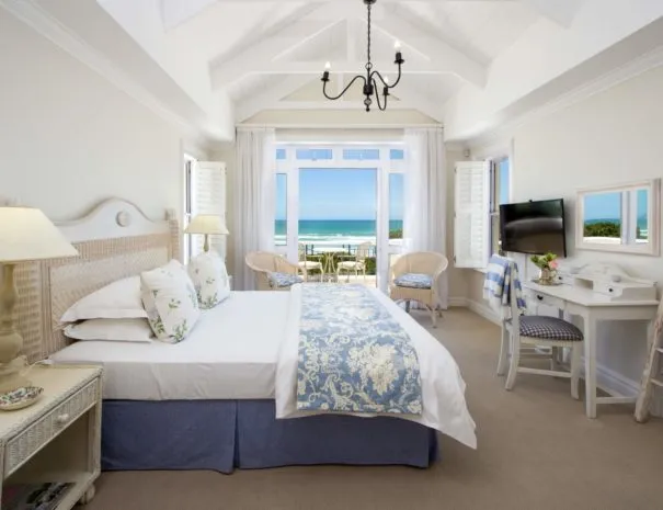 Bedroom with ocean view large bed and writing desk with TV