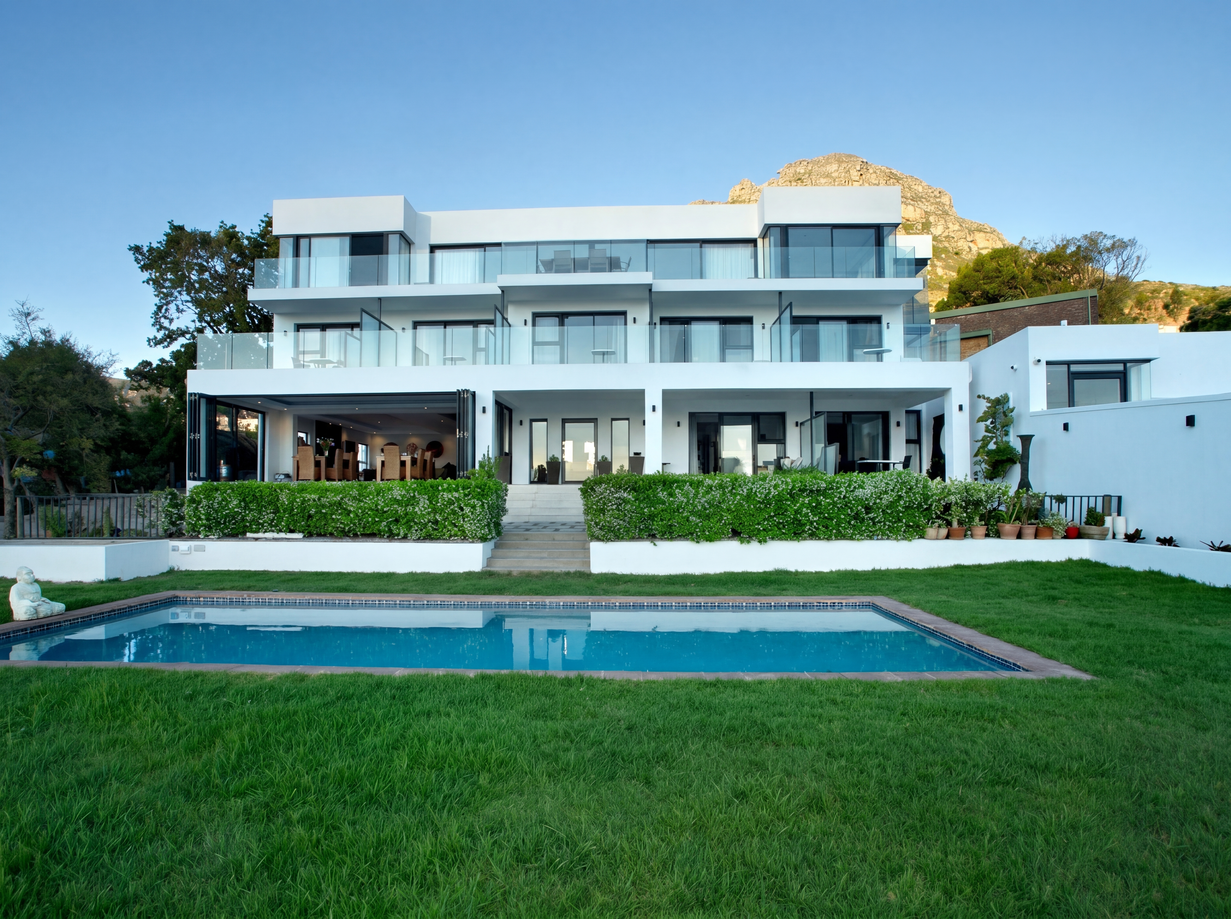 Modern threestory house with pool and garden mountain in background