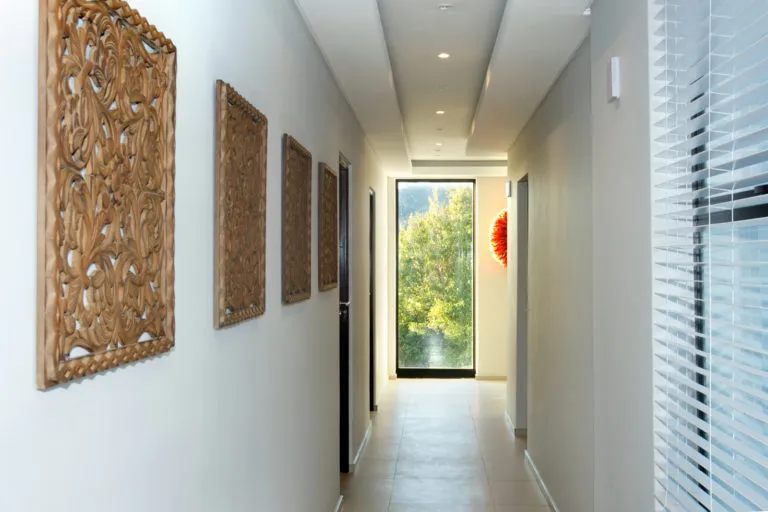 Hallway with wooden wall art doors and a large window at the end