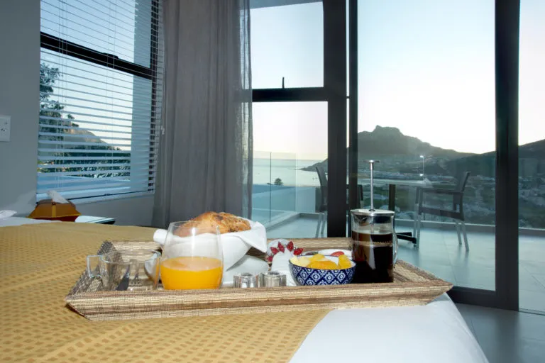 Breakfast tray on bed with ocean view through large windows