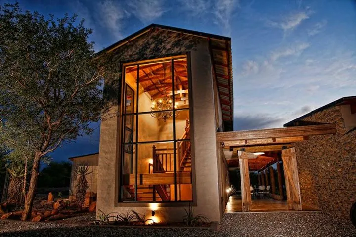 Modern house with large windows and wooden staircase lit up at dusk
