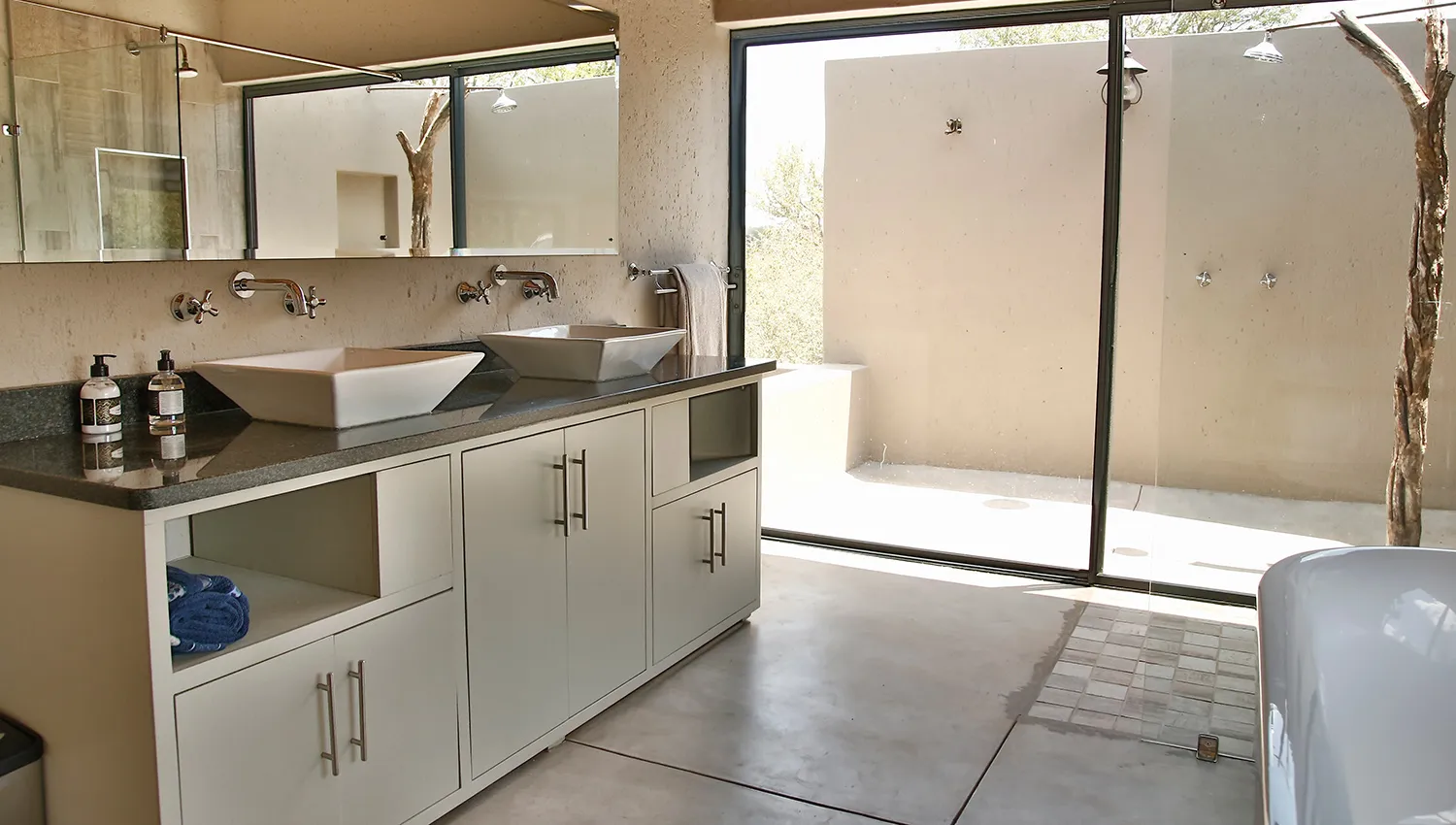 Modern bathroom with double sinks large mirror and open shower area