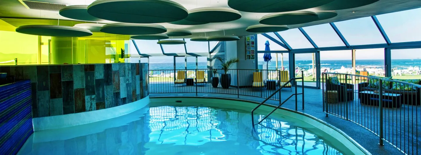 Indoor pool with large windows overlooking the ocean and lounge area