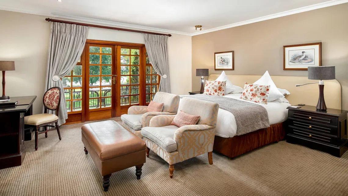 Cozy bedroom with a large bed armchairs and a view of a garden