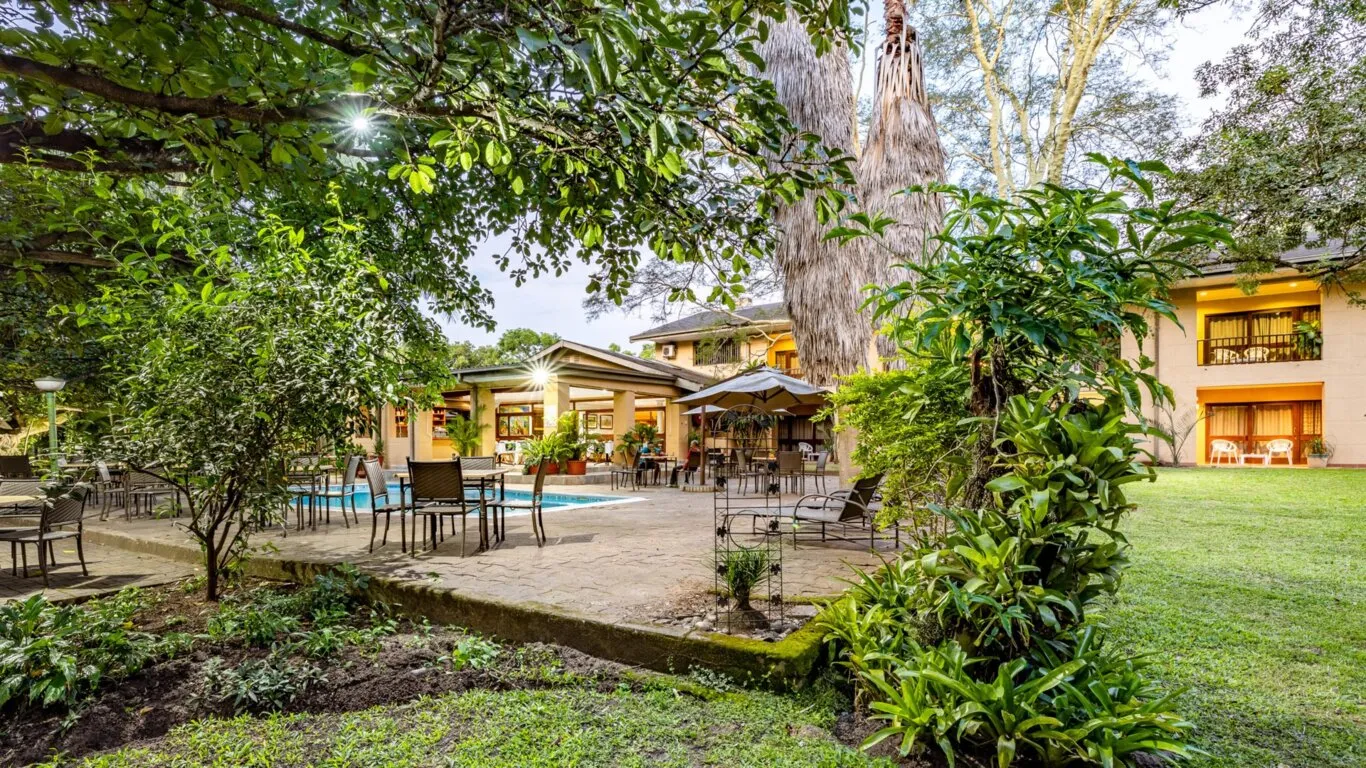 Outdoor seating area with pool surrounded by trees and a building in background