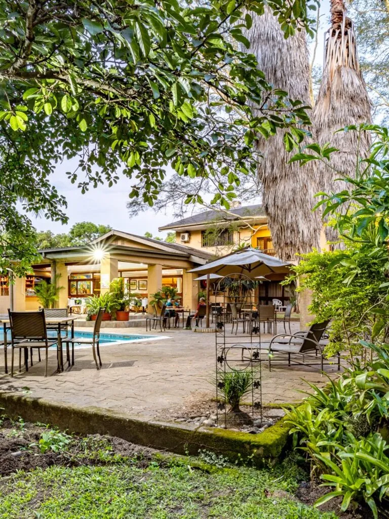 Outdoor seating area with pool and lush greenery around a large house