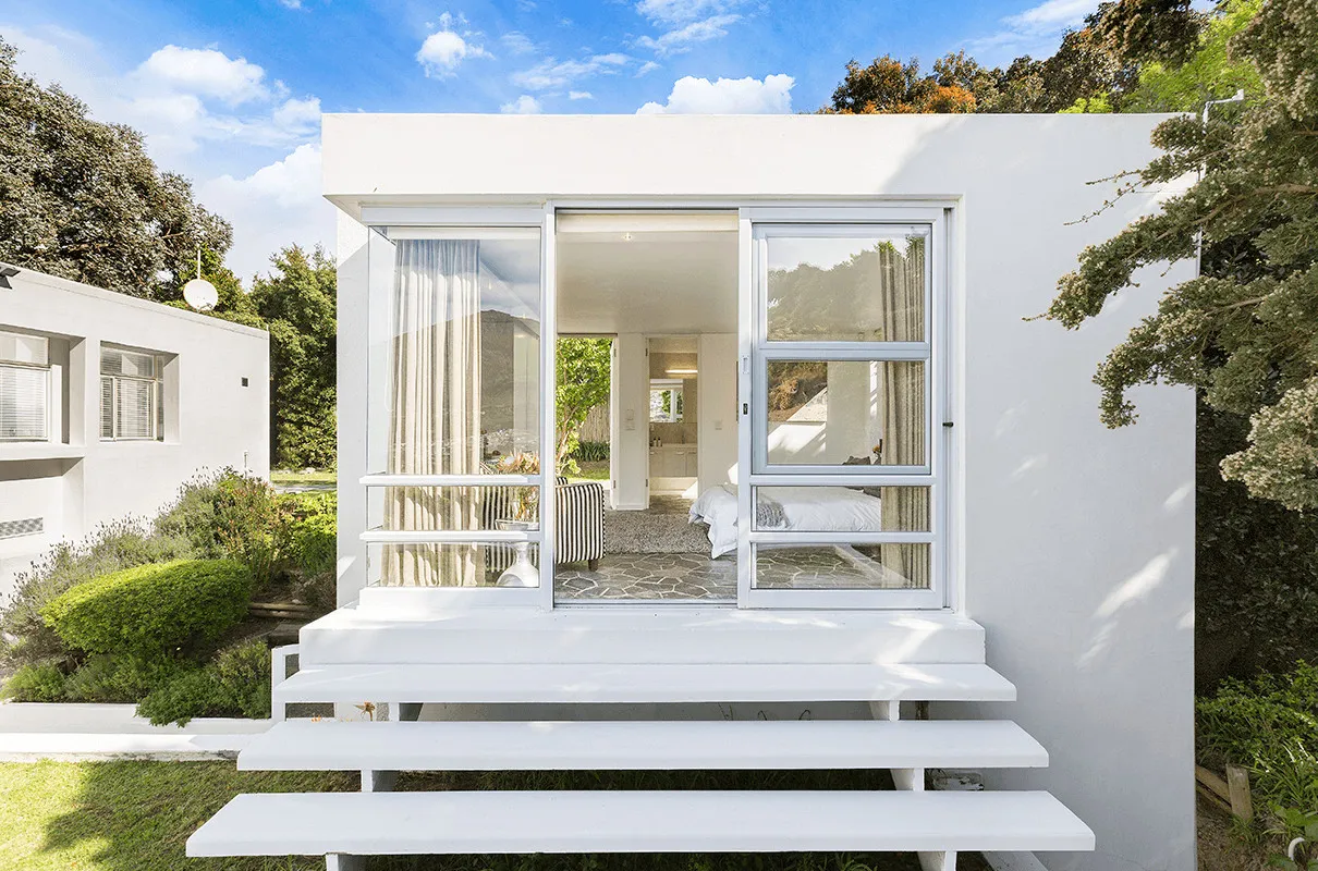 Modern white house with open sliding doors garden and blue sky