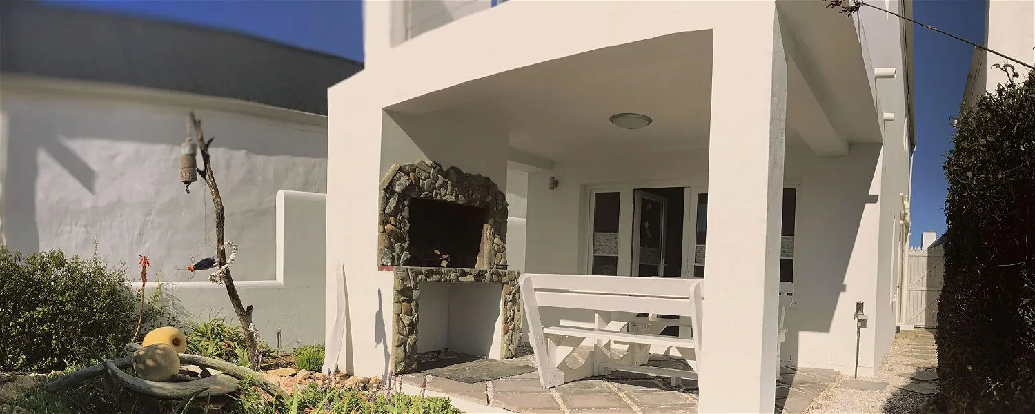 White patio with builtin stone barbecue bench and garden area