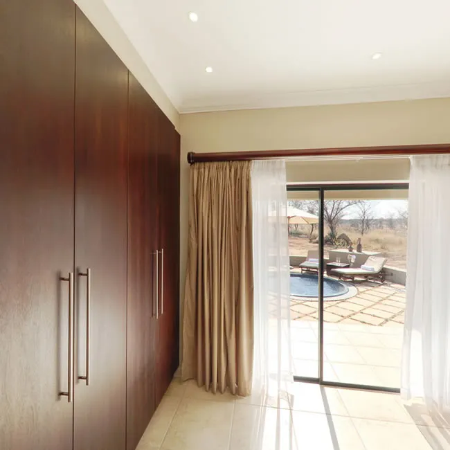 Modern bedroom with large windows overlooking a patio and pool area