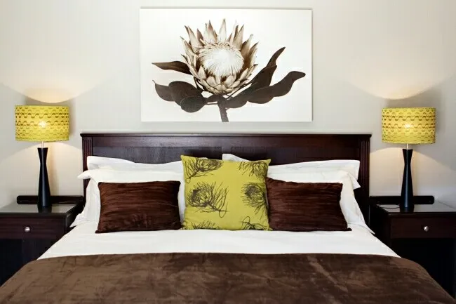 Bedroom with a bed two bedside tables lamps and a floral wall art