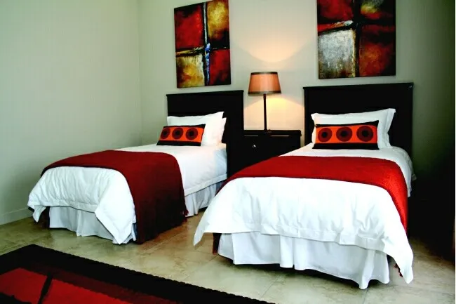 Two single beds with red and white bedding in a modern bedroom