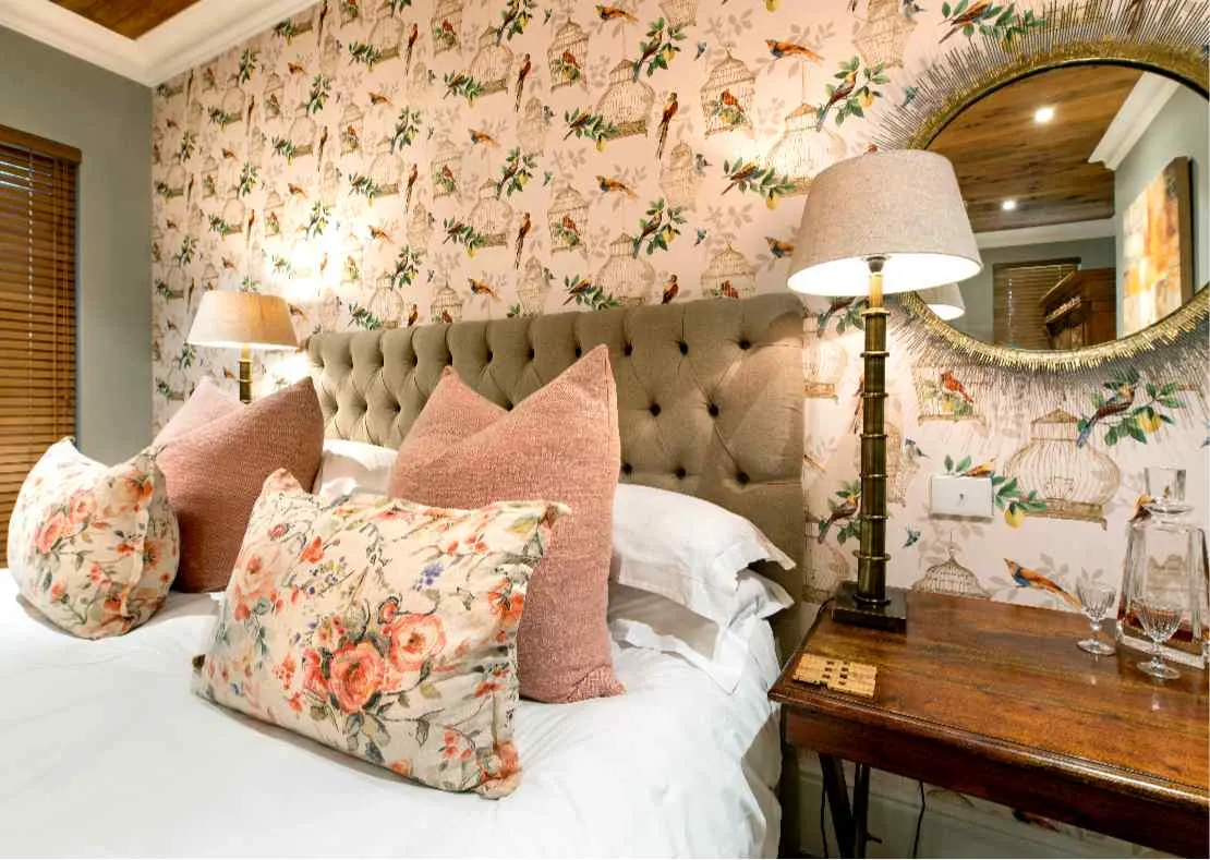 Cozy bedroom with floral wallpaper large bed and bedside table with lamp