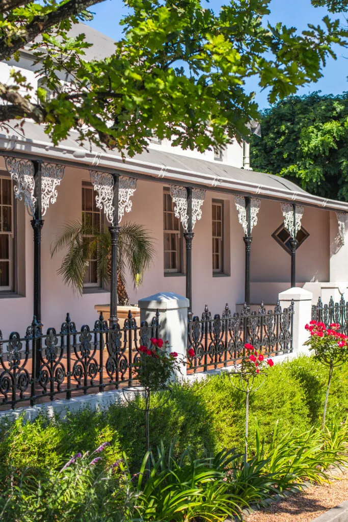 Colonialstyle building with ornate balcony iron fence and lush greenery in front