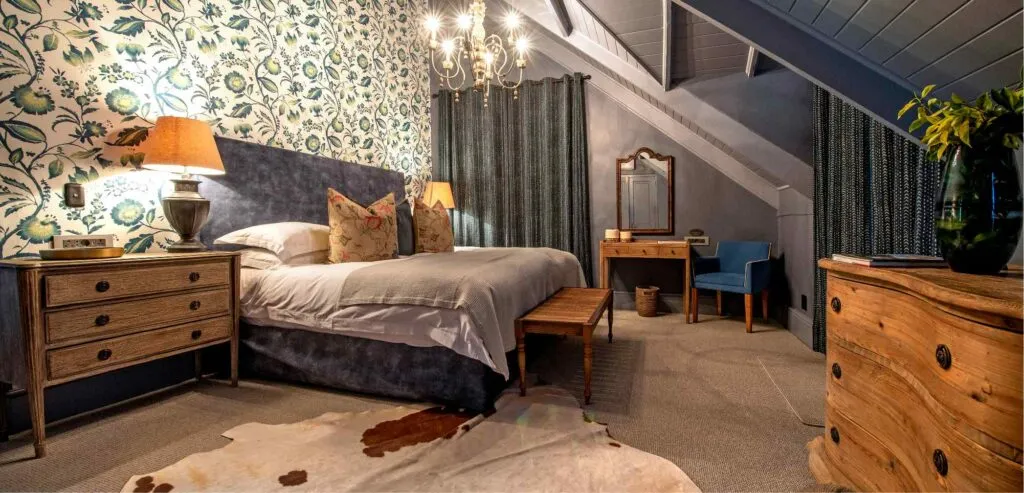 Cozy bedroom with patterned wallpaper wooden furniture and a cowhide rug