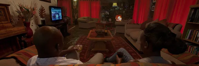 A couple watches TV in a cozy warmly lit living room