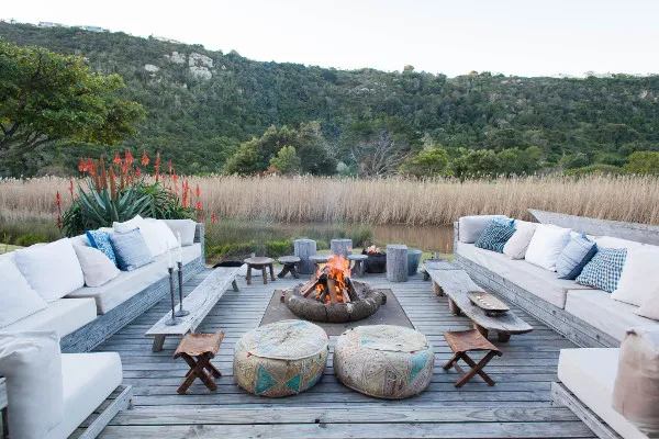 Outdoor lounge area with a fire pit surrounded by nature and seating