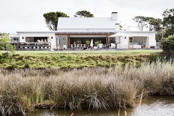 Modern house with outdoor seating area near a pond and tall grasses