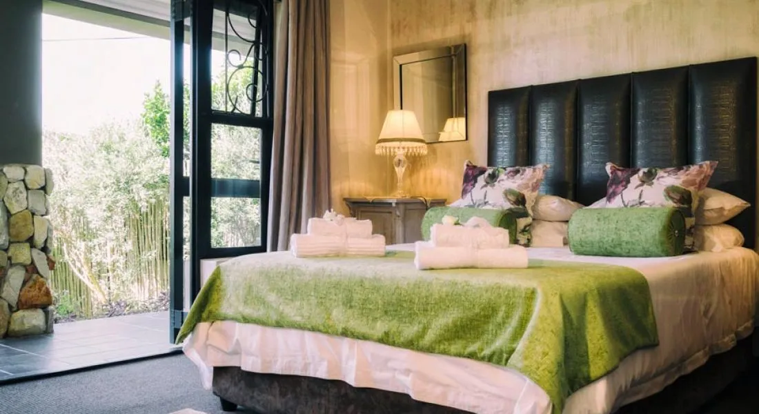 Cozy bedroom with green bedding open door to garden and bedside lamp